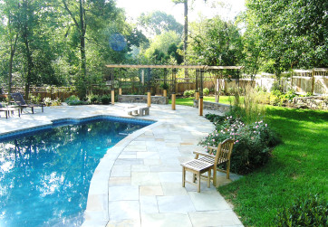 Circular bluestone pool deck integrates irregular pool shape into new site design