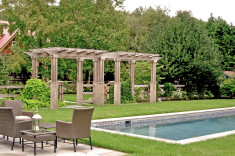 Wooden arbor creating threshold between pool and back patio area