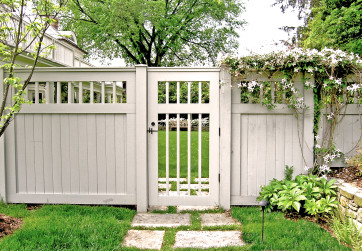 A white wooden fence provides privacy and extends the home’s architectural style into the garden