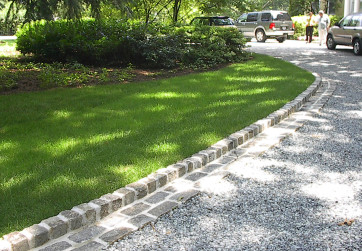 An entry drive is lined with stone cobbles to ensure a clean line between the lawn and gravel