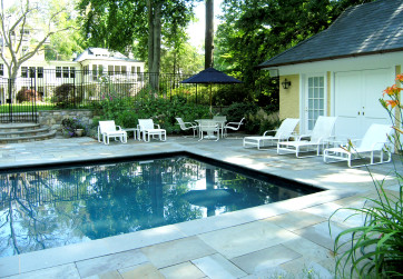 An existing pool is enhanced by a new pool house and deck framed with gardens and stone retaining walls