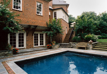 The stone and brick deck nestle the pool into the site