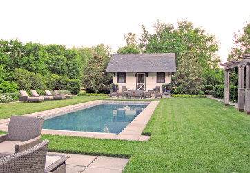 Wide stone coping surrounds a serene pool located in a lush lawn panel