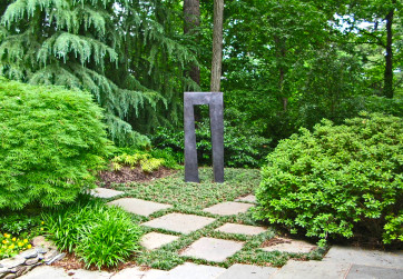 Lush woodland plantings create a dramatic backdrop for sculpture piece.
